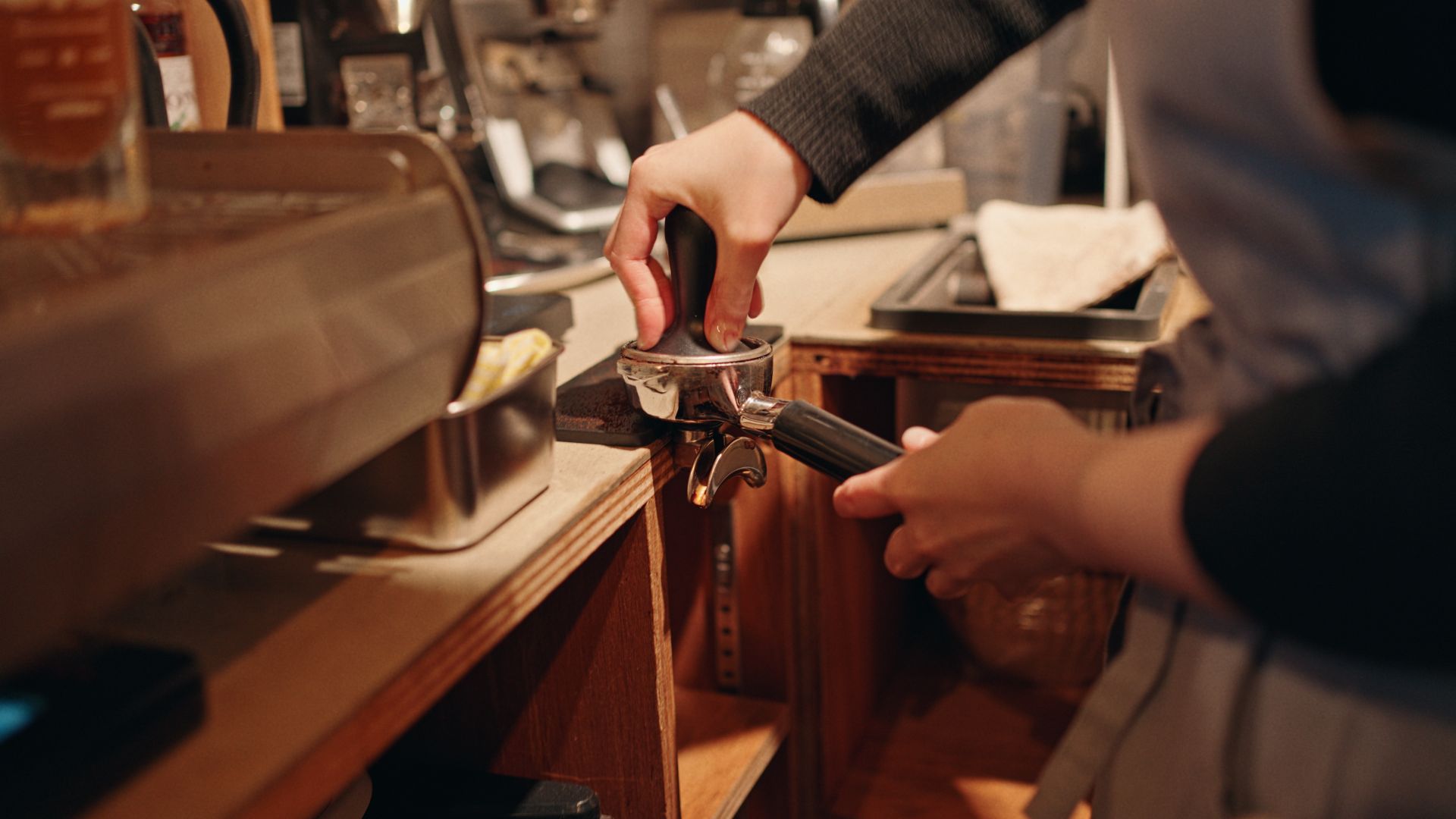 Barista tamping fresh coffee grounds into a portafilter