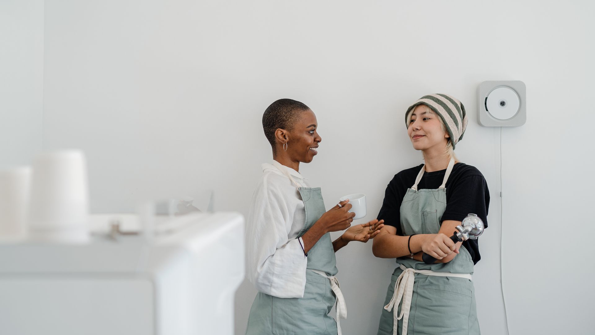 Two baristas in aprons behind the coffee bar