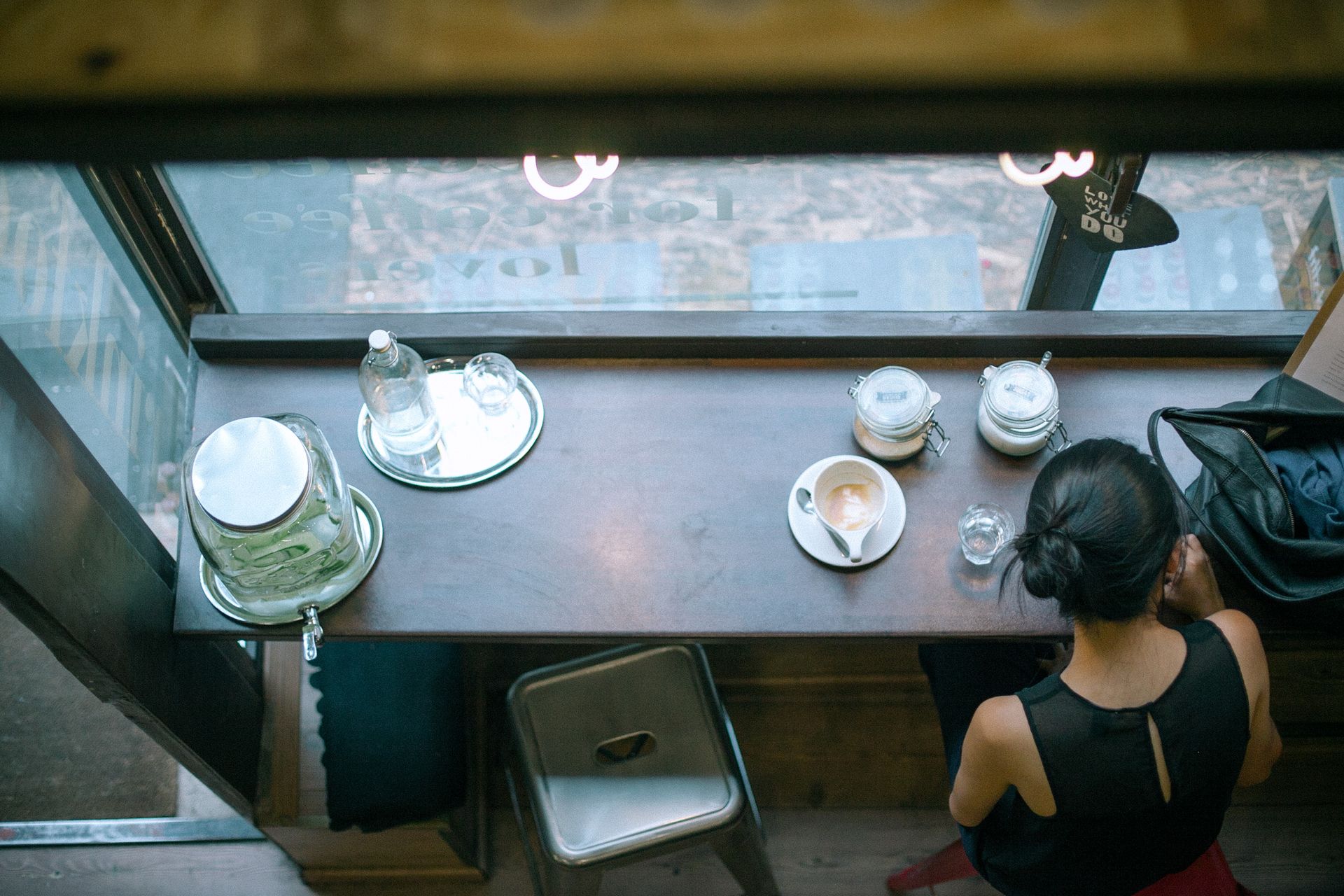 Customer with a finished flat white at a café window bar