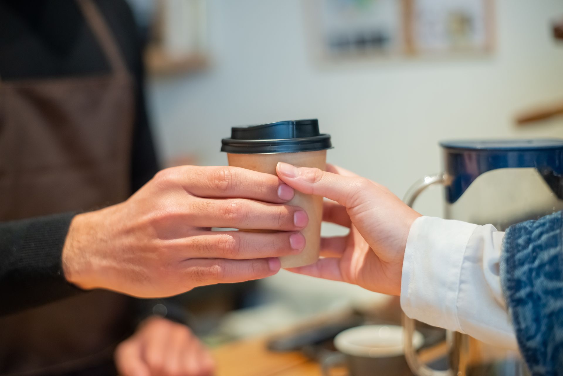A freshly made coffee being placed on the table in front of a seated customer